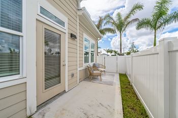 A patio with a chair and a table is in front of a house. at The Boardwalk at Tradition, Port St Lucie, Florida
